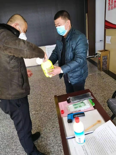七台河公司东风矿矿党委副书记王占寒在督导检查防疫工作的同时为单位提供测温仪、消毒液、喷壶等防护用品。。。。。图为王占寒（左）正与党员对办公场所进行消毒。。。。。（于秀娟摄）